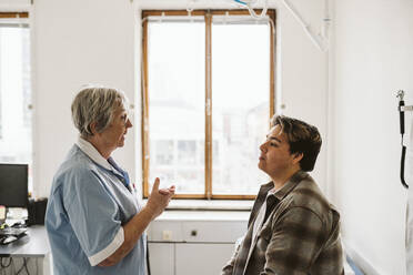 Älterer medizinischer Experte im Gespräch mit einem männlichen Patienten während einer Konsultation in der Klinik - MASF23936