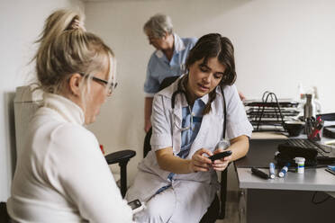 Medizinische Fachangestellte diskutiert mit einem Patienten in einer medizinischen Klinik über ein Glaukomgerät - MASF23965