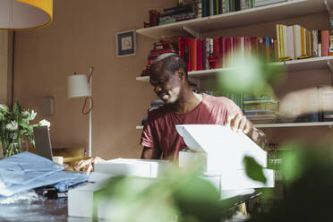 Männlicher Berufstätiger, der im Büro zu Hause am Laptop arbeitet - MASF24173