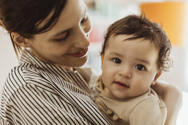 Smiling mother carrying male toddler at home - MASF24210