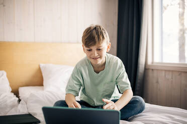 Blond boy E-learning through laptop at home - MASF24270