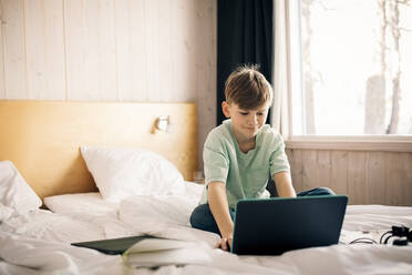 Boy using laptop while studying at home - MASF24276