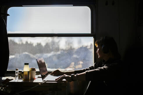 Weibliche Unternehmerin blickt während einer Zugfahrt durch das Fenster - MASF24293
