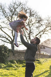 Father catching daughter while enjoying weekend during springtime - JAQF00668
