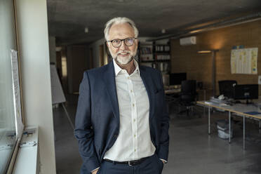 Male entrepreneur with eyeglasses standing at office - UUF23448