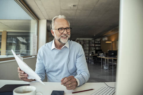 Smiling male entrepreneur doing video call on computer at office - UUF23493