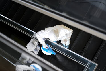 Sanitäter dekontaminieren das Treppenhaus eines Büros mit Desinfektionsmitteln - ABIF01377