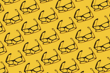 Muster von Reihen von einfachen klassischen Brillen flach auf gelbem Hintergrund gelegt - GEMF04811
