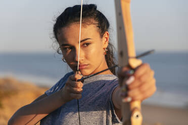 Determined young woman aiming with bow and arrow - JRVF00979