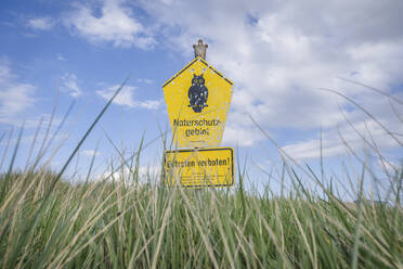 Aus dem hohen Gras ragendes Hinweisschild im Naturschutzgebiet Fehmarn - KEBF01977