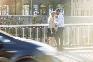 Romantisches Paar, das sich küsst, während es am Geländer steht - WPEF04721