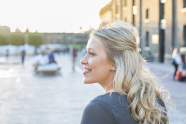 Smiling young woman looking away while spending leisure time outdoors - WPEF04726