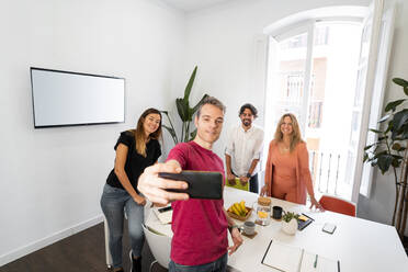 Männlicher Unternehmer macht Selfie mit Kollegen im Coworking-Büro - MPPF01862