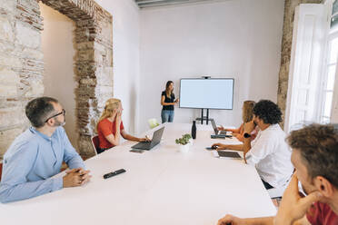 Weibliche Fachkraft, die eine Besprechung auf einer Projektionsfläche im Sitzungssaal eines Coworking-Büros leitet - MPPF01868