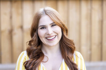 Beautiful happy redhead woman against wooden wall - WPEF04740