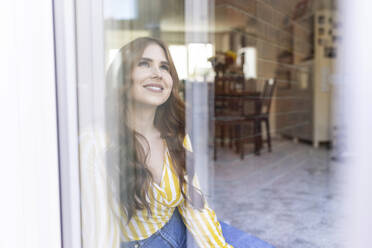 Lächelnde schöne Frau, die wegschaut, gesehen durch ein Fenster - WPEF04777