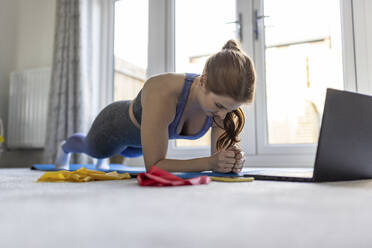 Redhead woman practicing plank while exercising at home - WPEF04787