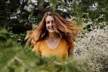 Woman with tousled hair dancing in garden - AFVF08791