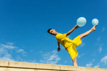 Young man balancing while dancing with balloons - XLGF02055