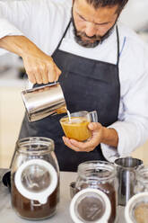 Koch gießt Milch ein, während er in der Großküche eines Restaurants arbeitet - PGF00594