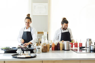 Lächelnde männliche und weibliche Köche bei der Arbeit im Restaurant - PGF00615