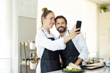 Glückliche Köche machen Selfie mit Handy in der Küche eines modernen Restaurants - PGF00618
