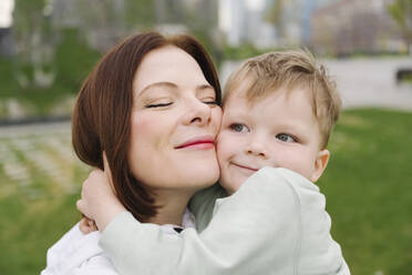 Cute son embracing mother at public park - EYAF01625