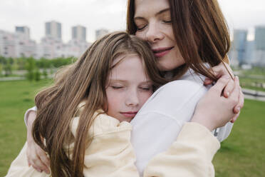 Daughter embracing mother in park - EYAF01627