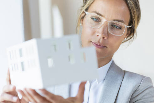 Female architect holding architectural model in office - SBOF03927
