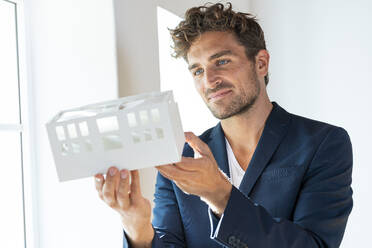 Männlicher Architekt hält ein Architekturmodell im Büro - SBOF03936