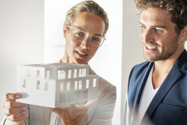 Männlicher und weiblicher Fachmann mit architektonischem Modell arbeiten zusammen im Büro - SBOF03948
