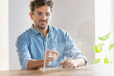 Männlicher Architekt benutzt futuristisches digitales Tablet bei der Arbeit im Büro - SBOF03957