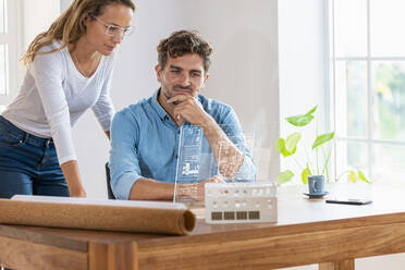 Männlicher und weiblicher Fachmann, der über eine transparente digitale Tafel im Büro nachdenkt - SBOF03958