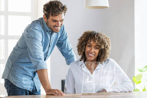 Businessman standing by colleague using futuristic digital tablet in office - SBOF03964