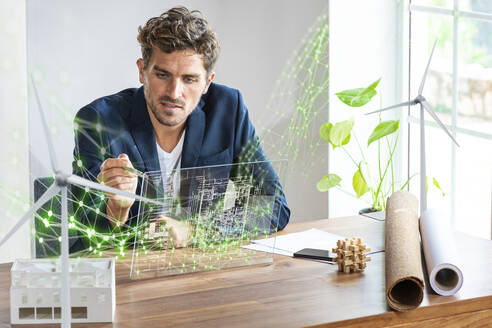 Male architect using futuristic digital tablet while sitting by desk - SBOF03969