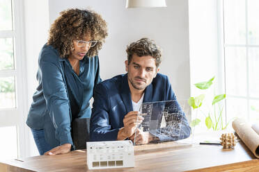 Männliche und weibliche Architekten arbeiten im Büro an einem futuristischen digitalen Tablet - SBOF03970