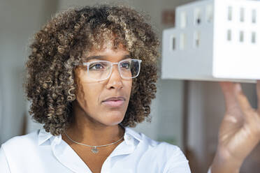 Female entrepreneur examining architectural model at office - SBOF03990