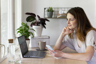 Lächelnde weibliche Fachkraft bei einem Videogespräch am Laptop im Büro zu Hause - AFVF08806