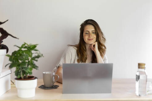 Berufstätige Frau arbeitet am Laptop an der Wand im Heimbüro - AFVF08811