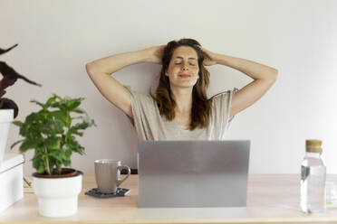 Frau mit Hand im Haar in der Nähe der Wand im Heimbüro - AFVF08812