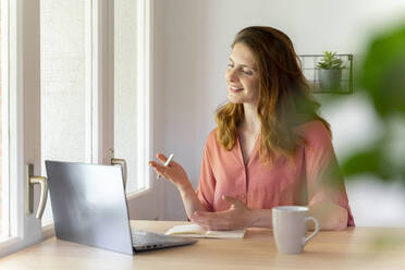 Geschäftsfrau gestikuliert während eines Videogesprächs auf dem Laptop im Heimbüro - AFVF08818