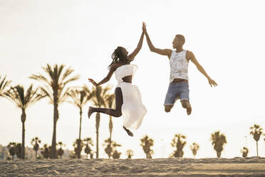 Playful couple giving high-five while playing at beach - MPPF01883