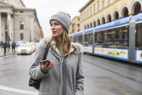 Beautiful woman looking away while standing on city street - WPEF04810