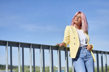 Young woman with eyes closed leaning on railing during sunny day - KIJF03971