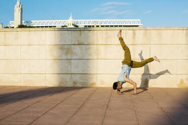 Mid adult dancer practicing handstand on footpath during sunny day - XLGF02063