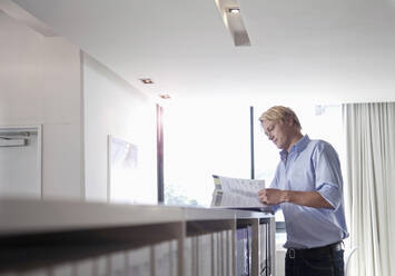 Männlicher Fachmann, der im Büro Dokumente durchgeht - AJOF01474