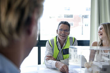 Männlicher Architekt lächelt während einer Besprechung im Büro - AJOF01485