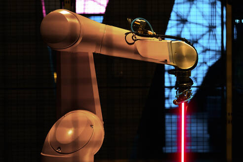 Beleuchteter Roboterarm mit Laser im Werk - PNAF01827