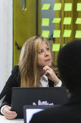 Geschäftsfrau mit Laptop während einer Besprechung im Büro sitzend - PNAF01831