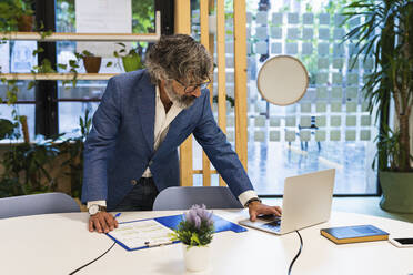 Männlicher Unternehmer arbeitet am Laptop im Büro - PNAF01856